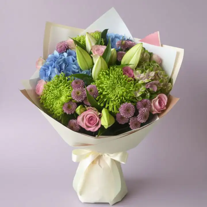 Enchanted Rose & Hydrangea Bloom 1 A beautifully hand-tied rose and hydrangea bouquet with lush green leaves in a soft lighting setting.