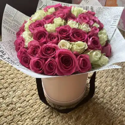 A luxury pink rose hat box featuring a dense arrangement of soft pastel roses in a stylish round container.