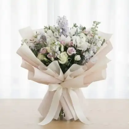 A hand-tied delphinium and rose bouquet featuring vibrant blue stalks and soft pastel petals in a bridal arrangement.