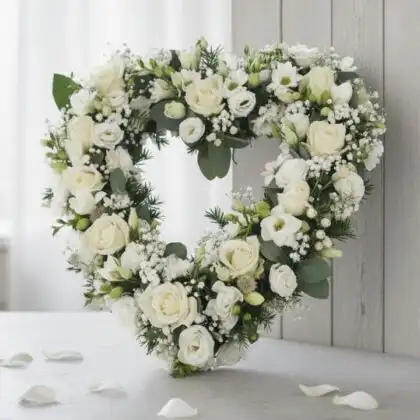 An elegant open heart flowers for funeral arrangement featuring premium white roses and seasonal greenery on a wooden stand.