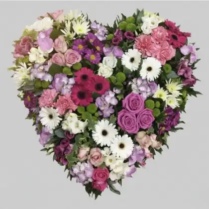A professional floral arrangement designed as a broken heart funeral tribute featuring white and red flowers.