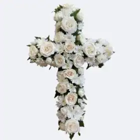 A handcrafted funeral cross flowers arrangement featuring fresh white roses and chrysanthemums on a woven background.