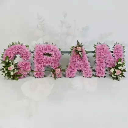 A beautiful floral letter tribute spelling GRAN made of white chrysanthemums and pink roses for funeral services.