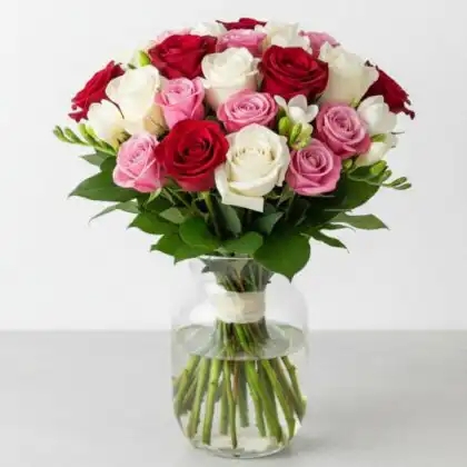A vibrant bouquet red and white roses mixed with pink spray roses and lush green leaves.