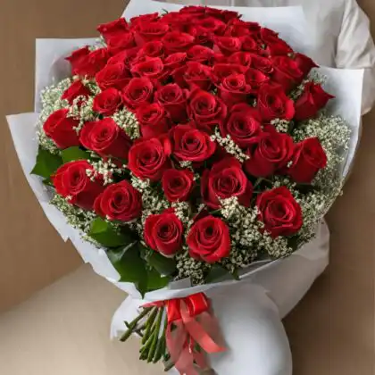 A large bouquet of red roses accented with white baby's breath and wrapped in premium white floral paper.