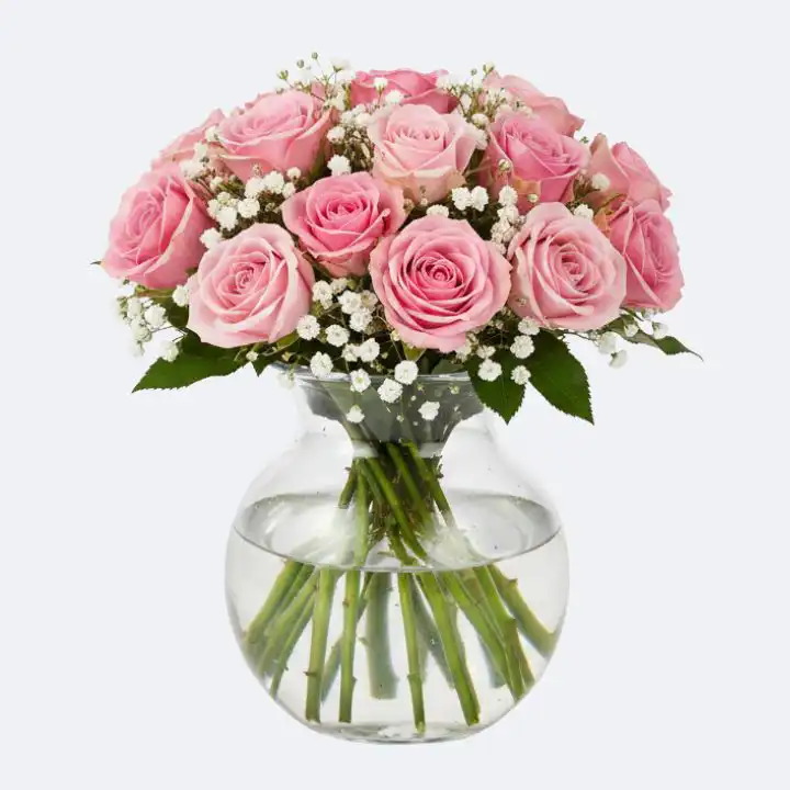 Fresh Pink Rose hand tied in a Glass Vase 1 A lush arrangement of fresh pink roses in a vase with white baby's breath accents and green leaves.