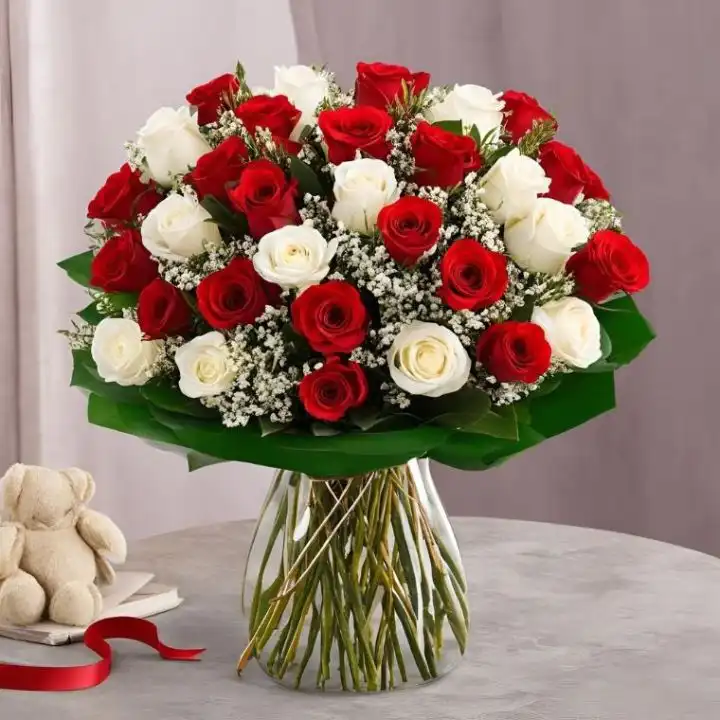 Hand-Tied Red and White Rose Bouquet with Baby's Breath 1 A fresh white and red roses bouquet arranged with baby's breath in a clear glass vase on a wooden table.
