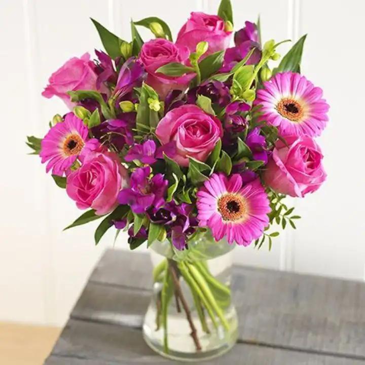 A vibrant bouquet featuring a pink gerbera rose paired with elegant lilies in a decorative arrangement.