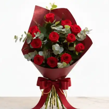A luxury red rose bouquet with eucalyptus leaves wrapped in premium brown craft paper for a wedding.