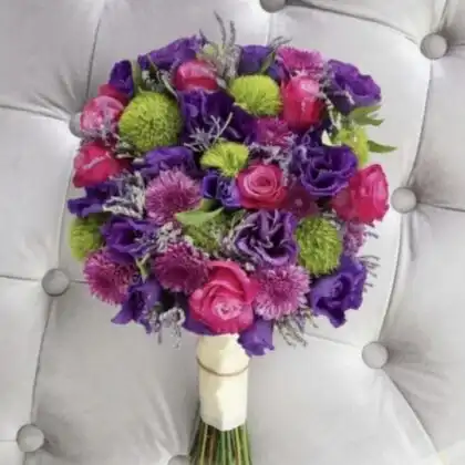 A hand-tied roses and lisianthus bouquet featuring vibrant pink roses and deep purple lisianthus with green accents.