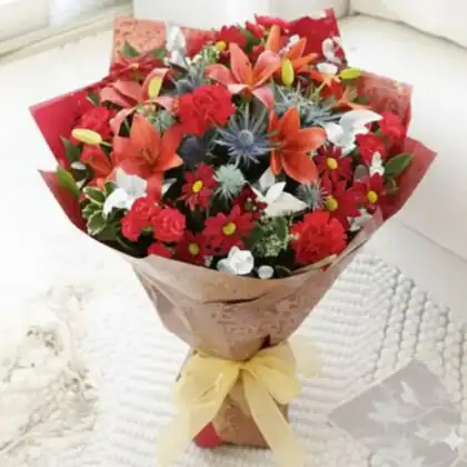 A beautiful orange lily bouquet in a decorative wrap, showcasing vibrant petals and fresh greenery.